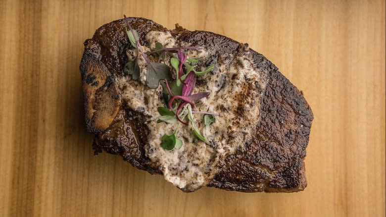 Steak with herb garnish on cutting board