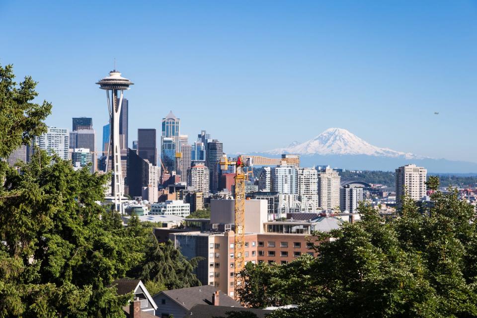 a classic view of seattle downtown district with the famous space needle tower and the mount rainier snow covered mountain in the background in washington state, usa