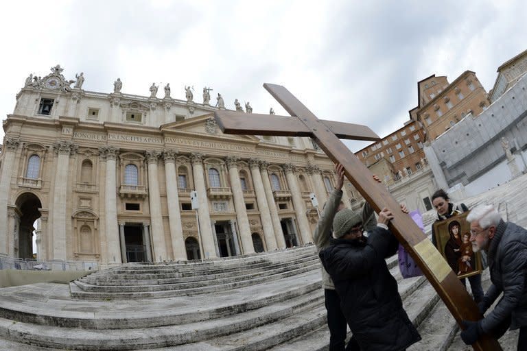Some of the faithful carry a cross on the steps of St Peter's Basilica on February 11, 2013