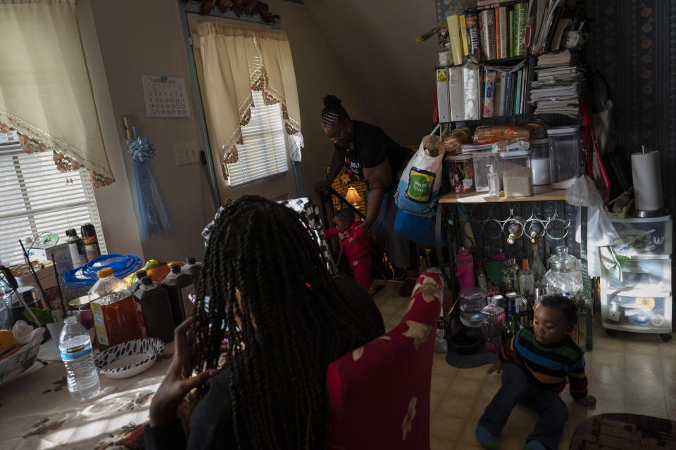 Ansonia Lyons, left, finishes a snack while her mother, Shelonda Lyons, takes care of her son, Adrien Lyons, as her nephew, Malik Lyons-Law, plays in the kitchen in Birmingham, Ala., on Saturday, Feb. 5, 2022. After two miscarriages, Ansonia became pregnant in 2020, and it was difficult. Doctors initially told her she was suffering from regular morning sickness, though she was vomiting blood. Ultimately, she was eventually diagnosed with an excessive vomiting disorder, hyperemesis gravidarum, and was extremely dehydrated. (AP Photo/Wong Maye-E)