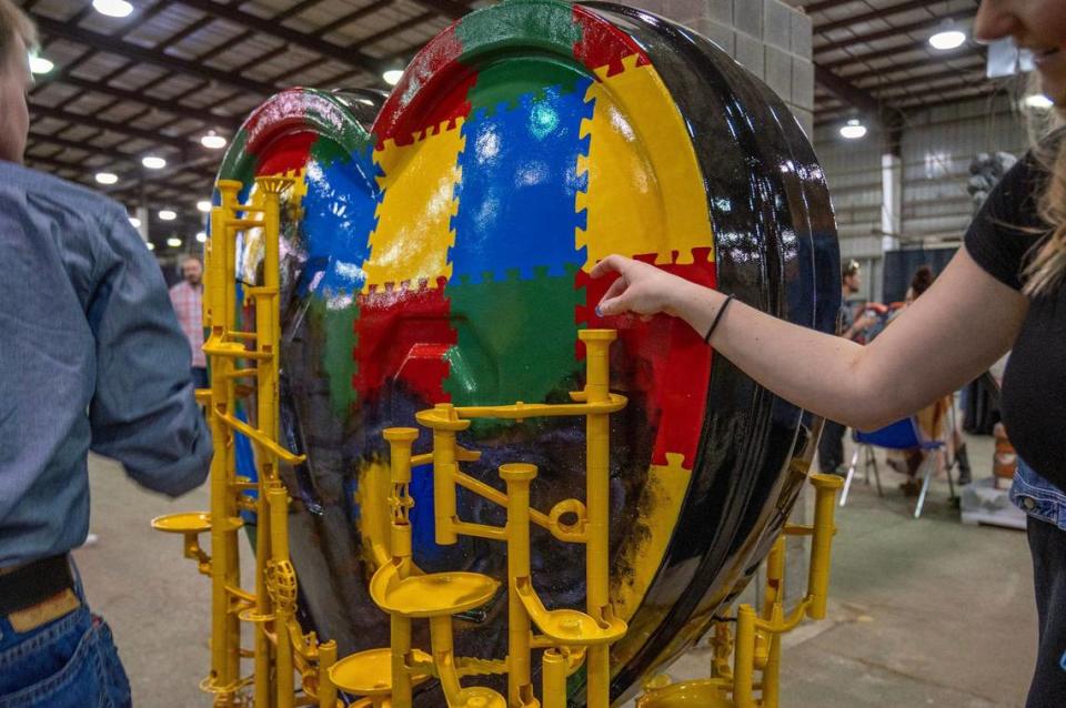 A visitor places a blue marble into a contraption featured in the heart display titled “The Blue Marble” by artist Miranda McDermott. Emily Curiel/ecuriel@kcstar.com