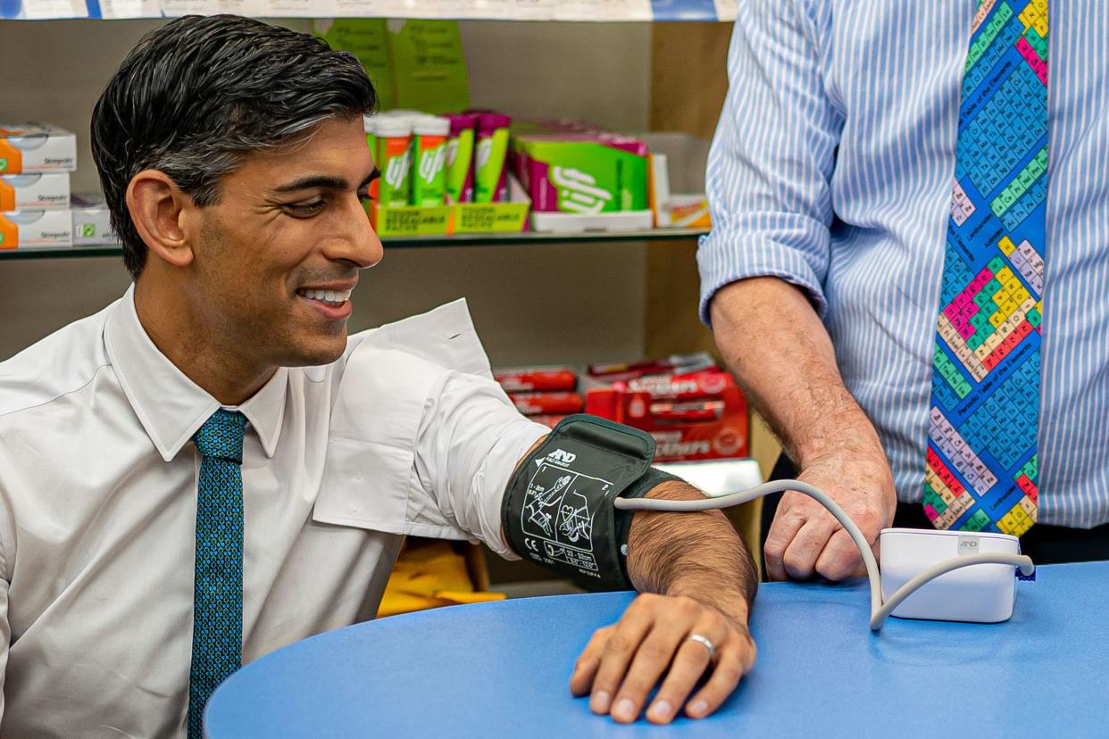 Britain's Prime Minister Rishi Sunak reacts as he has his blood pressure checked by pharmacist Peter Baillie, during a visit to a GP surgery and pharmacy in Weston, southern England on May 9, 2023. Sunak's government has announced that more pharmacists will now be able to prescribe medication previously given by doctors, to try to relieve pressure on the health service. (Photo by Ben Birchall / POOL / AFP) (Photo by BEN BIRCHALL/POOL/AFP via Getty Images)