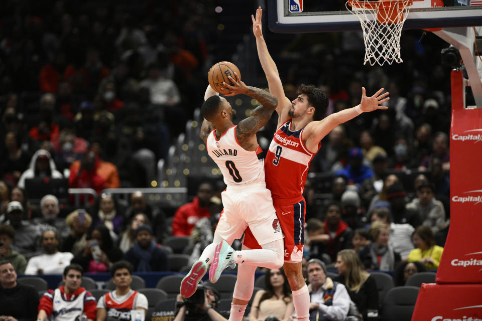 Portland Trail Blazers guard Damian Lillard (0) goes to the basket against Washington Wizards forward Deni Avdija (9) during the first half of an NBA basketball game, Friday, Feb. 3, 2023, in Washington. Avdija was charged with a foul on the play. (AP Photo/Nick Wass)