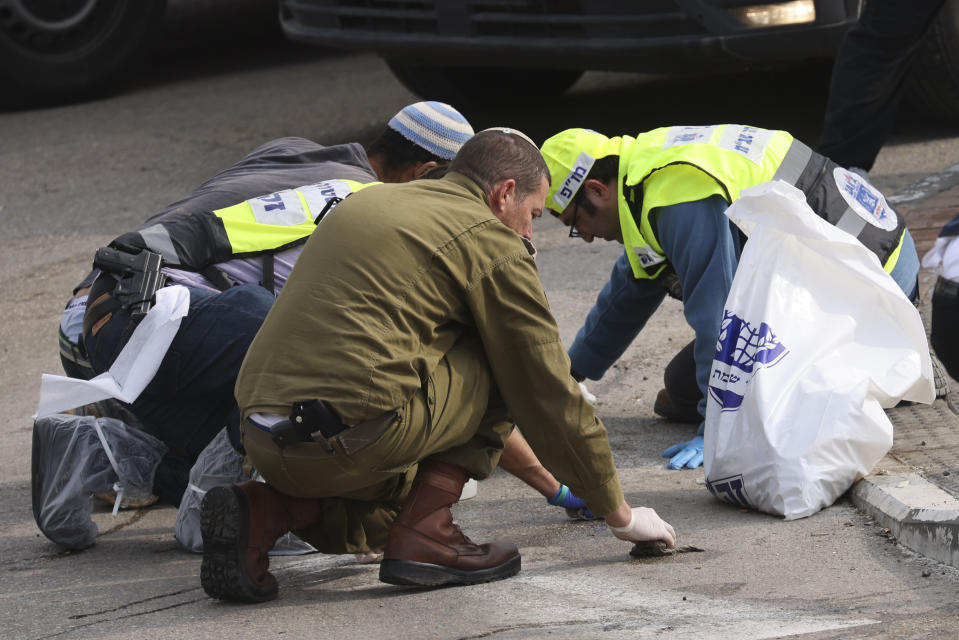 Members of Israeli Zaka Rescue and Recovery team and an Israeli soldier clean blood from the site of an attack, at the Ariel Industrial Zone, near the West Bank Jewish settlement of Ariel, Tuesday, Nov. 15, 2022. A Palestinian killed two Israelis and wounded four others in an attack in a settlement in the occupied West Bank on Tuesday before he was shot and killed by Israeli security personnel, Israeli paramedics and Palestinian officials said. (AP Photo/Oren Ziv)