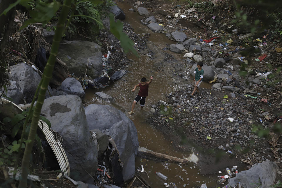 Anderson Zelaya and a friend play in a river littered with debris leftover from last year's October 2020 landslide, in Los Angelitos, El Salvador, Wednesday, July 28, 2021. The 2020 Atlantic hurricane season, one of the worst ever for Central America, wiped out homes and crops and displaced more than half a million people. (AP Photo/Salvador Melendez)