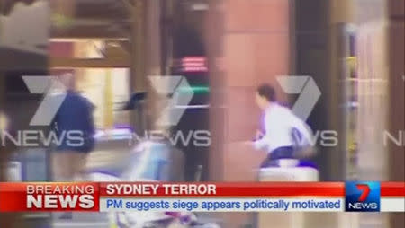 Two men (L in blue jacket; R in white shirt) are seen running out of the Lindt cafe, where hostages are being held, in this still image taken from video from Australia's Seven Network on December 15, 2014. REUTERS/Reuters TV via Seven Network