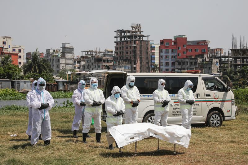 People, wearing protective suits, offer funeral prayers for a man who died due to coronavirus disease (COVID-19), before his burial at a graveyard in Dhaka