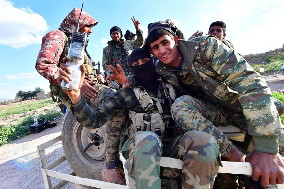 Fighters from the Syrian Democratic Forces gesture the