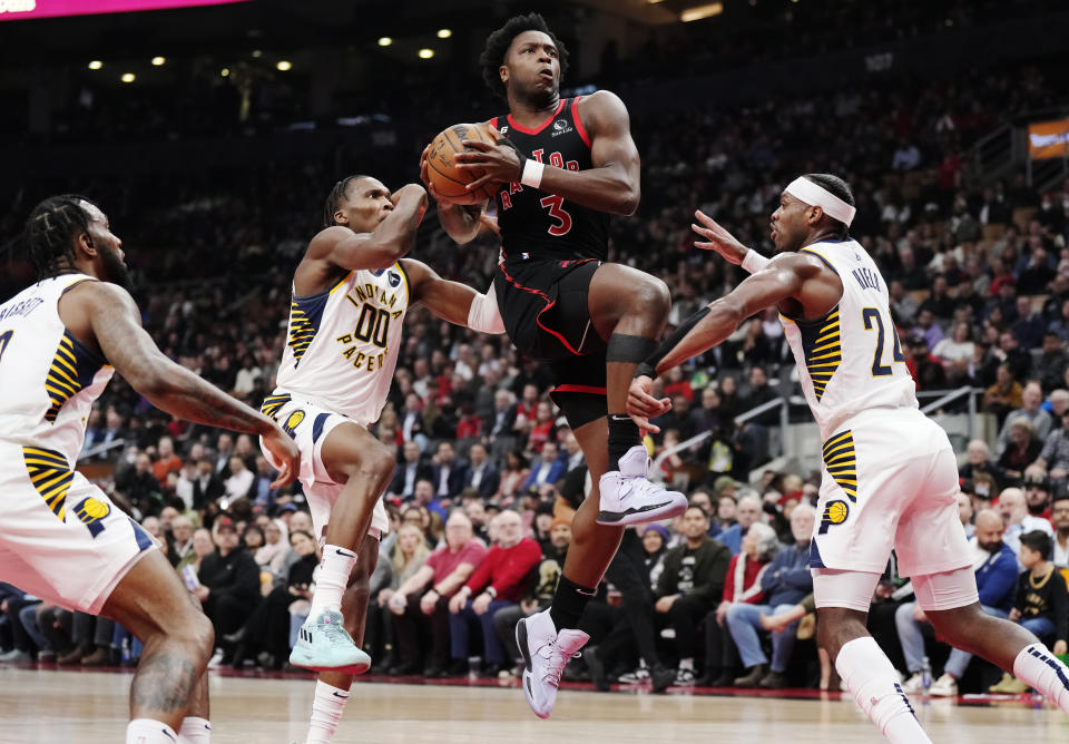 Toronto Raptors forward O.G. Anunoby (3) drives between Indiana Pacers guard Bennedict Mathurin (00) and Pacers guard Buddy Hield (24) during the first half of an NBA basketball game in Toronto, Wednesday, March 22, 2023. (Frank Gunn/The Canadian Press via AP)
