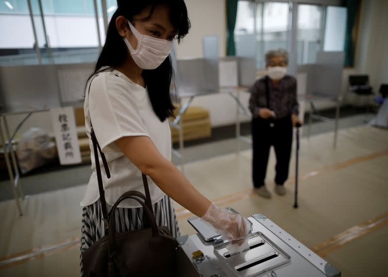 A voter wearing a ptotective face mask and vinyl gloves casts a ballot casts a ballot amid the coronavirus disease (COVID-19) outbreak, at a voting station for the Tokyo Governor election in Tokyo