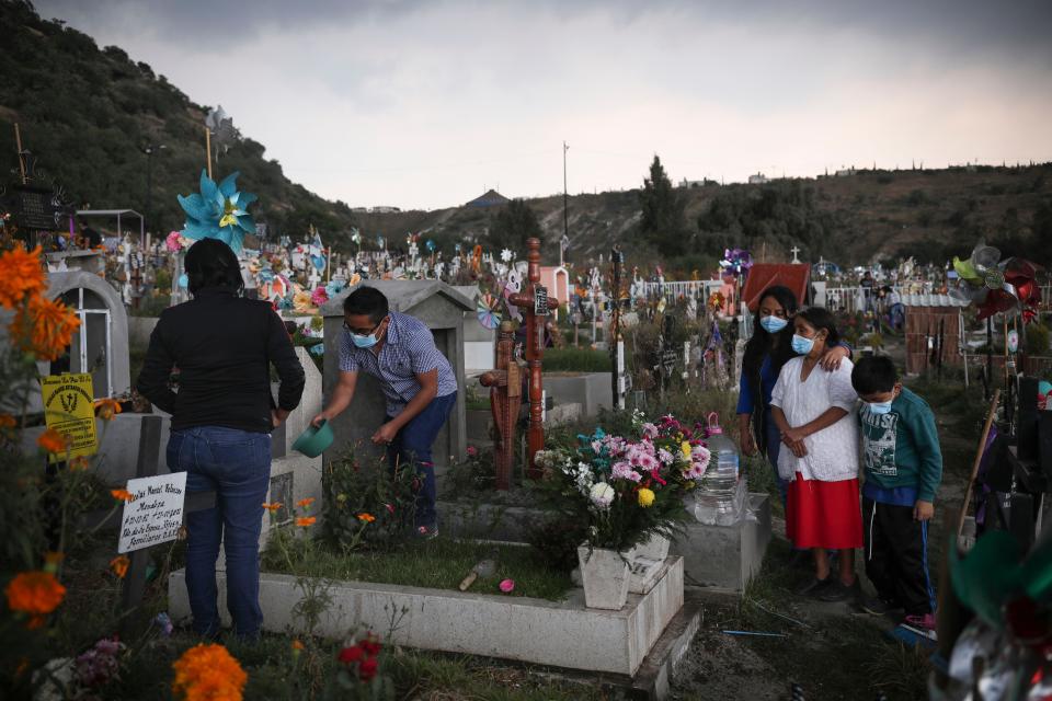 Family members tend to the grave of a relative in preparations for the Day of the Dead celebrations, at the Valle de Chalco municipal cemetery on the outskirts of Mexico City, Thursday, Oct. 28, 2021.