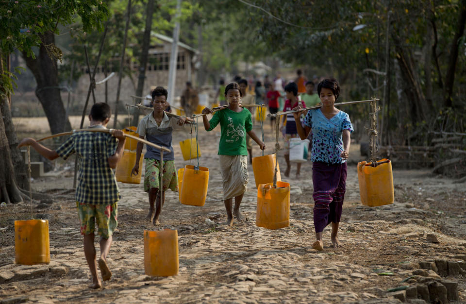 In this April 2, 2014 photo, residents of Dala, carry plastic containers filled with drinking water fetched from a natural water pond as others walk to collect water in the suburbs of Yangon, Myanmar. During the annual dry season in April and May, residents pay 10 kyat, 10 U.S. cents for each bucket of water and walk up to five kilometers (three miles) carrying the buckets full of water for the consumption of their families in this improvised neighborhood. (AP Photo/Gemunu Amarasinghe)