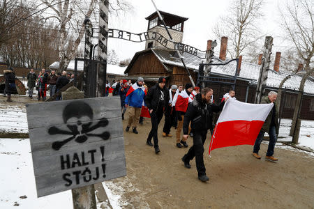 Far right ONR (National Radical Camp) activists walk past the "Arbeit Macht Frei" gate at the former Nazi German concentration and extermination camp Auschwitz, to pay tribute for Polish victims at the "death wall", during the ceremonies marking the 74th anniversary of the liberation of the camp and International Holocaust Victims Remembrance Day, in Oswiecim, Poland, January 27, 2019. REUTERS/Kacper Pempel