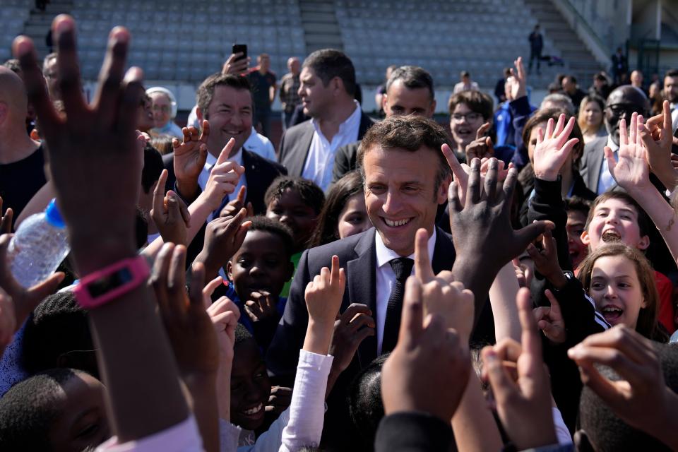 Children greet Macron greets as he campaigns in the Auguste Delaune stadium (AP)