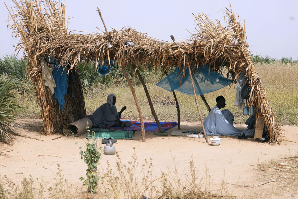 Aisha Ali's husband Mallam Baida Ali, right, prays in Darayami, northeastern Nigeria, Wednesday Oct. 26, 2022. When floodwaters reached their hut made of woven straw mats and raffia palms, they packed up what belongings they could and set off on foot with their eight youngest children. "While the flood was trying to destroy things, we were trying to save ourselves," said Aisha. Four of her children perished. (AP Photo/Sunday Alamba)