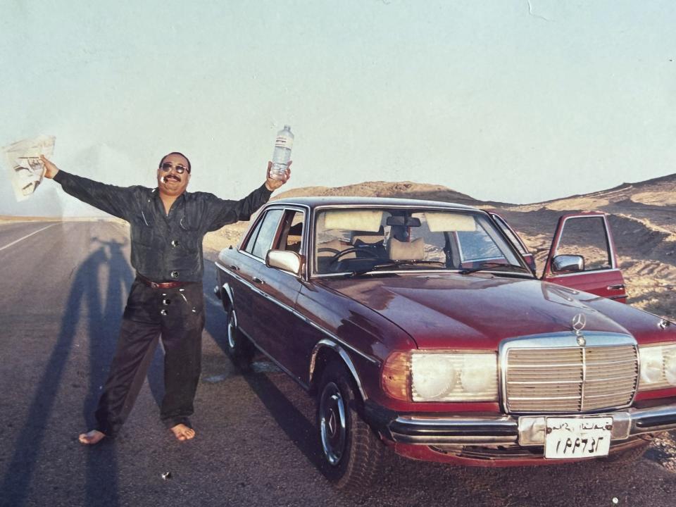 Moustafa Bassiouni stands next to his Mercedes Benz sedan during a break in a long drive from Cairo to Sharm El Sheik in the Sinai peninsula in 1997. Bassiouni, an intrepid photo assistant and driver for The Associated Press’ Cairo bureau, has died at age 64. His family said he died in a Cairo hospital on Saturday, June 10, 2023, after experiencing a heart attack. (AP Photo/Enric Marti)