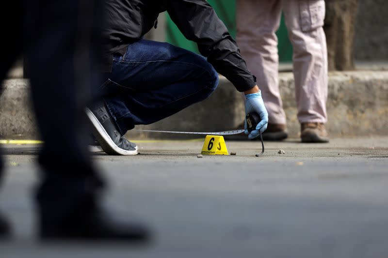 A police investigator works at a crime scene where a man was gunned down by unknown assailants, in Mexico City