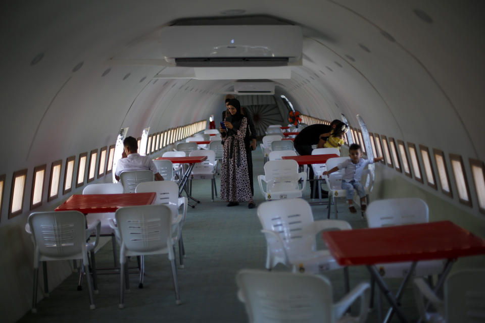 Palestinians visit a Boeing 707 after the plane was converted to a cafe restaurant, in Wadi Al-Badhan, near the West Bank city of Nablus, Wednesday, Aug. 11, 2021. The Palestinian territory has no civilian airport and those who can afford a plane ticket must catch their flights in neighboring Jordan. After a quarter century of effort, twins brothers, Khamis al-Sairafi and Ata, opened the “Palestinian-Jordanian Airline Restaurant and Coffee Shop al-Sairafi” on July 21, 2021, offering people an old airplane for customers to board. (AP Photo/Majdi Mohammed)