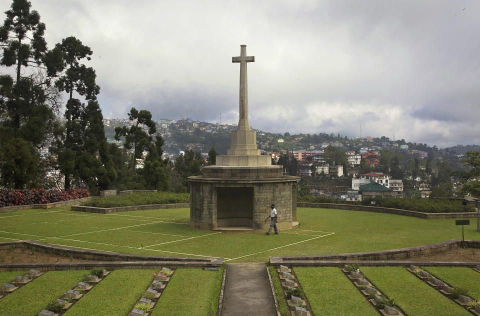In this Oct. 15, 2014 photo, a gardener walks past the preserved outlines of a tennis court around where some of the fiercest battles were fought in Kohima, now part of the Kohima War Cemetery, the final resting place of more than 1,420 Commonwealth servicemen of World War II, in Kohima, India. Between April and June 1944, Japanese and British Commonwealth forces fought across Kohima and the area around it in a battle that has been chosen as Britain's greatest battle by the National Army Museum, along with their battle in neighboring Imphal region. (AP Photo/Yirmiyan Arthur)