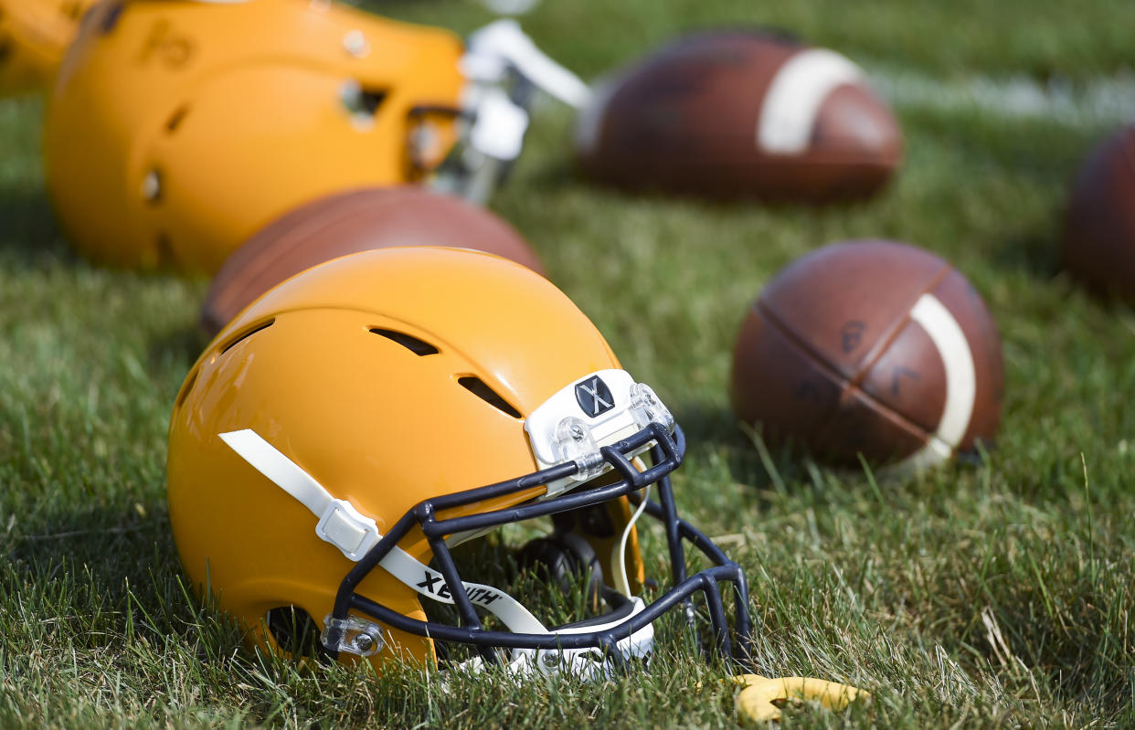 A detail photo of football helmets and balls on the ground during practice. (Photo by Ben Hasty/MediaNews Group/Reading Eagle via Getty Images)