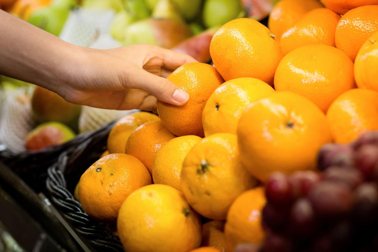 woman's hand choosing orange  from the food counter at the supermarket.woman's hand choosing orange  from the food counter at the supermarket.