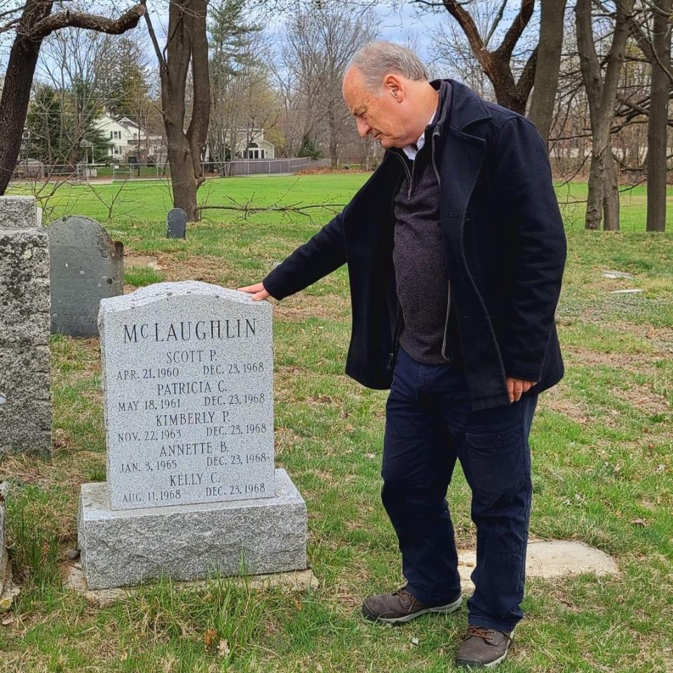 Portsmouth Athenaeum contract archivist Roland Goodbody gazes at a gravestone in Portsmouth's South Cemetery bearing the names of five members of the McLaughlin family who died in a fire just days before Christmas in 1968.