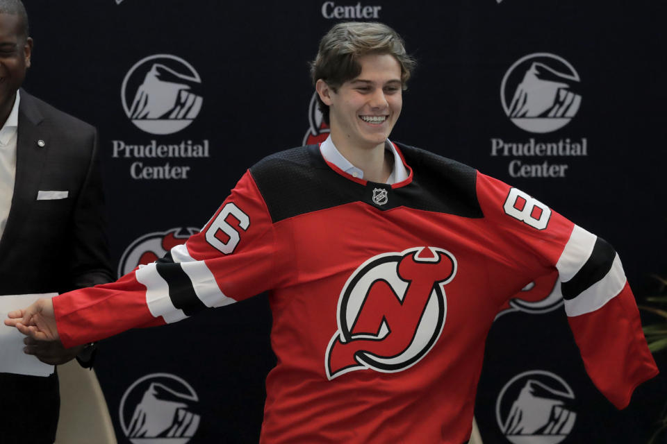 New Jersey Devils forward Jack Hughes, the No. 1 overall pick in the 2019 NHL draft, puts on a jersey during a news conference introducing the prospect to local media, Tuesday, June 25, 2019, in Newark, N.J. (AP Photo/Julio Cortez)