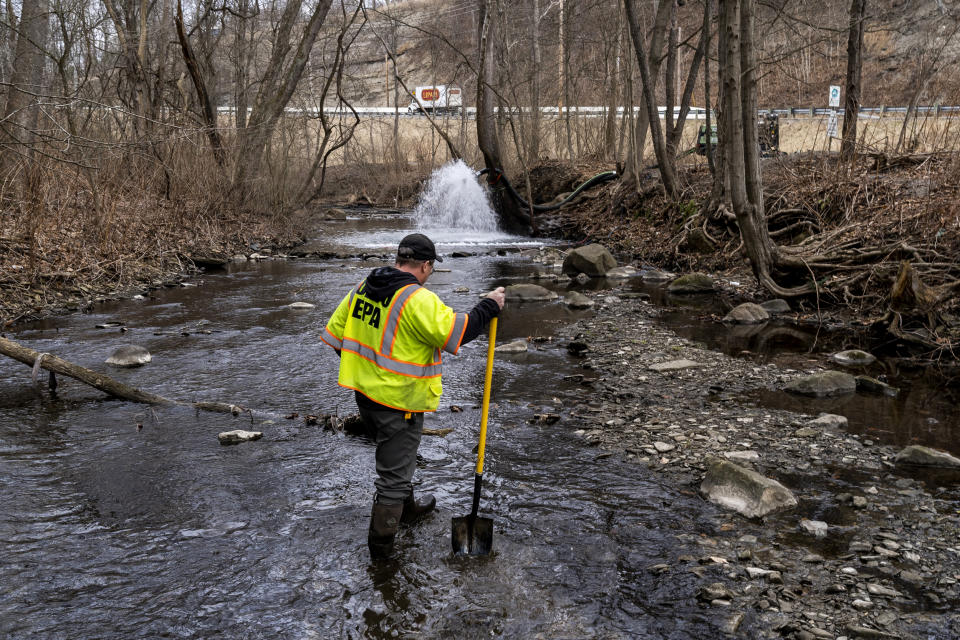 An Ohio EPA Emergency Response worker looks for signs of fish and also agitates the water in Leslie Run creek to check for chemicals that have settled at the bottom following a train derailment on Feb. 20, 2023, in East Palestine. (Michael Swensen / Getty Images)