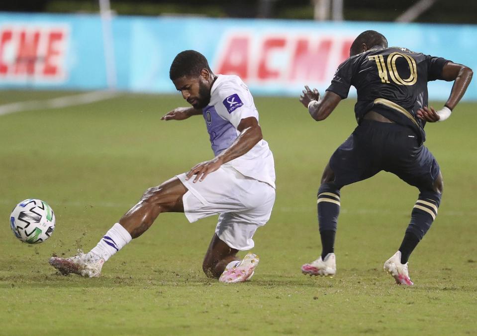 Orlando City's Ruan, left, keeps the ball from Philadelphia player Jamiro Monteiro, right, during an MLS Is Back tournament soccer game in Orlando, Fla., Monday, July 20, 2020. (Stephen M. Dowell/Orlando Sentinel via AP)