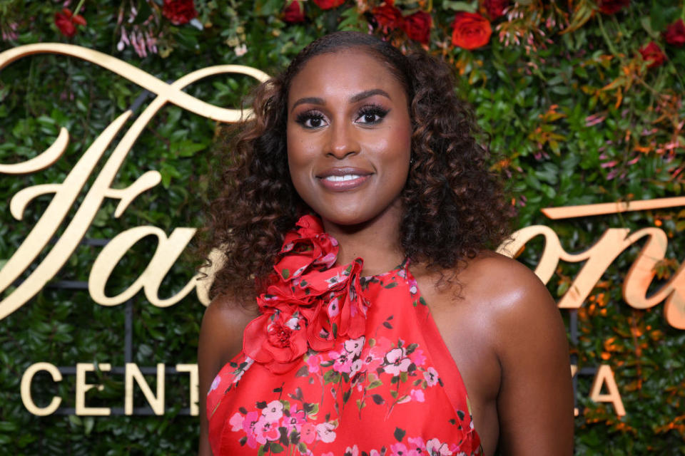 Issa Rae smiles against a flower bush