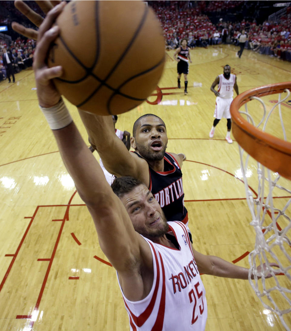 Chandler Parsons (25) de los Rockets de Houston trata de encestar ante la presión del defensor de los Trail Blazers de Portland Nicolas Batum en el juego de postemporada del domingo 20 de abril de 2014 que se jugó en Houston. (Foto de AP/David J. Phillip)