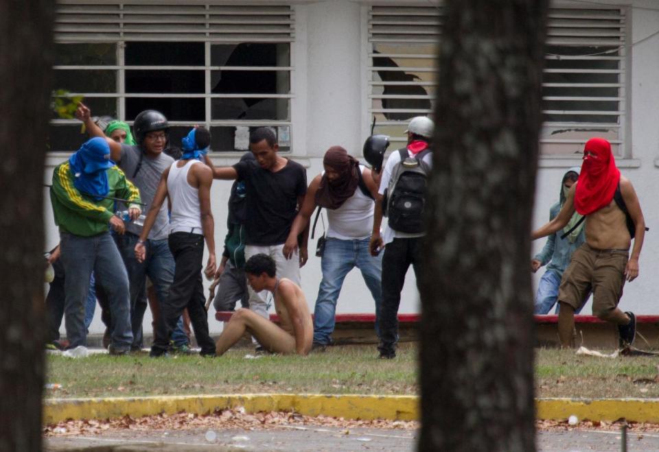 Partidarios del gobierno golpean a un estudiante opositor, quien fue desnudado, durante enfrentamientos en la Universidad Central de Venezuela (UCV), en el marco de protestas contra el gobierno en Caracas, Venezuela, el jueves 3 de abril de 2014. (Foto AP/Fernando Llano)