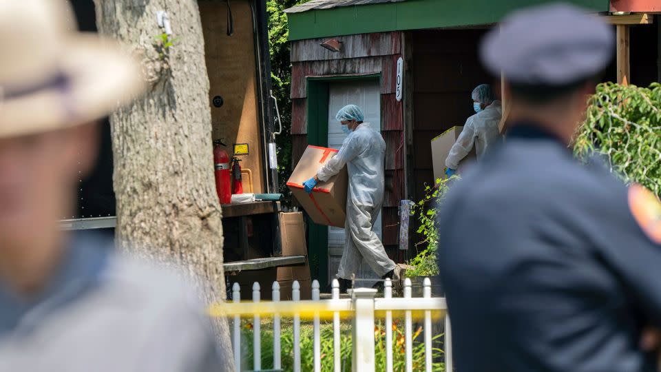 Crime laboratory officers removed boxes from the home. - Jeenah Moom/AP