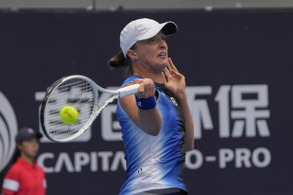 Iga Swiatek of Poland hits a return shot against Sara Sorribes Tormo of Spain during the first round of the women's singles match in the China Open tennis tournament at the Lotus Court in Beijing, Monday, Oct. 2, 2023. (AP Photo/Andy Wong)