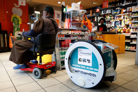 A man does his shopping at a store using an autonomous robot, shaped and inspired by Star Wars R2D2, in a test for the delivery of groceries by Franprix supermarket chain in the 13th district of Paris, France, April 17, 2019. REUTERS/Charles Platiau