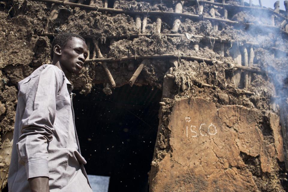 Ash drifts into the face of David Luo Kuang, 18, as he stands outside the doorway of his still-smoldering home that was burned in the recent fighting, after government forces on Friday retook from rebel forces the provincial capital of Bentiu, in Unity State, South Sudan, Sunday, Jan 12, 2014. On Sunday senior South Sudanese government officers inspected the recaptured town of Bentiu, in northern Unity State, that was the scene of intense fighting between government and rebel forces, while a South Sudanese government official claimed rebels had badly damaged petroleum facilities in the state. (AP Photo/Mackenzie Knowles-Coursin)