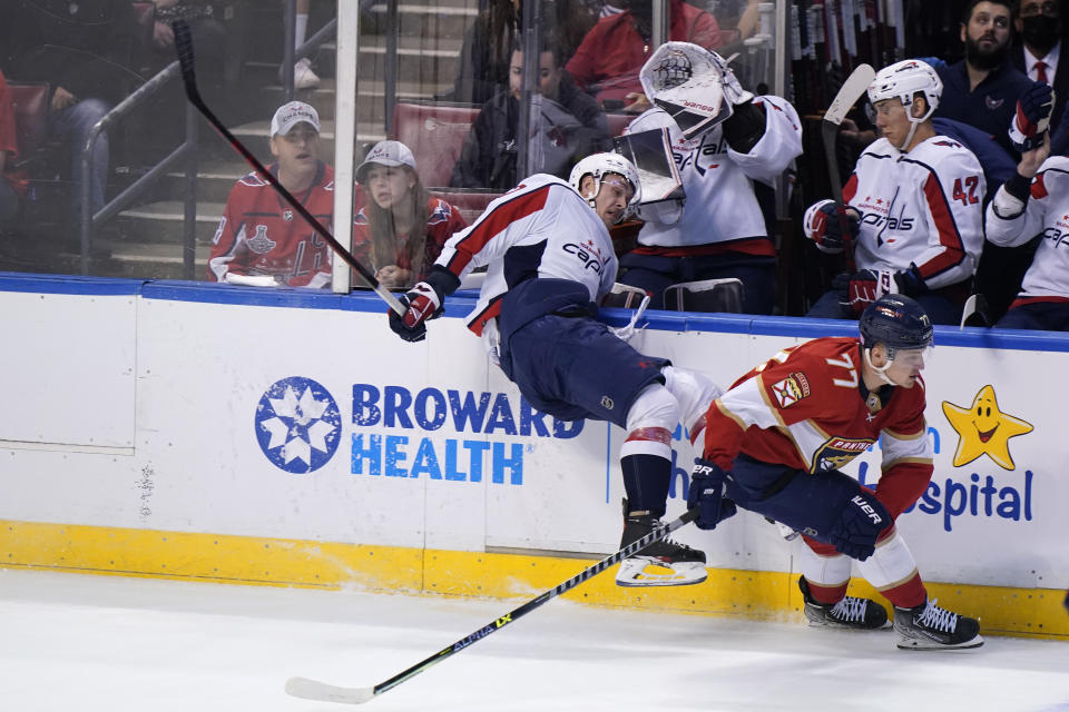 Florida Panthers center Frank Vatrano (77) slams Washington Capitals left wing Beck Malenstyn into the boards during the first period of an NHL hockey game, Tuesday, Nov. 30, 2021, in Sunrise, Fla. (AP Photo/Wilfredo Lee)