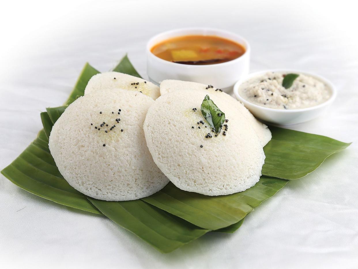 south Indian Dish, Idli (white) on banana leaves with coconut chutney and spicy vegetable sambhar.