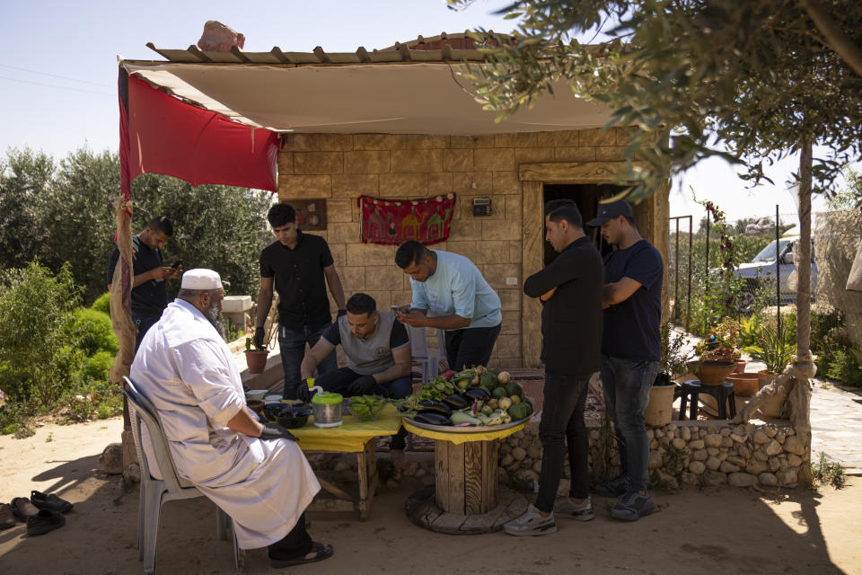 A group of Palestinian friends make a "Lasima," at a garden in Khuzaa, Gaza Strip, Saturday, May 20, 2023. Palestinians in the southern Gaza Strip call it “watermelon salad.” But this delicacy popular in the area at this time of year is far from the sweet, refreshing taste the name evokes. (AP Photo/Fatima Shbair)