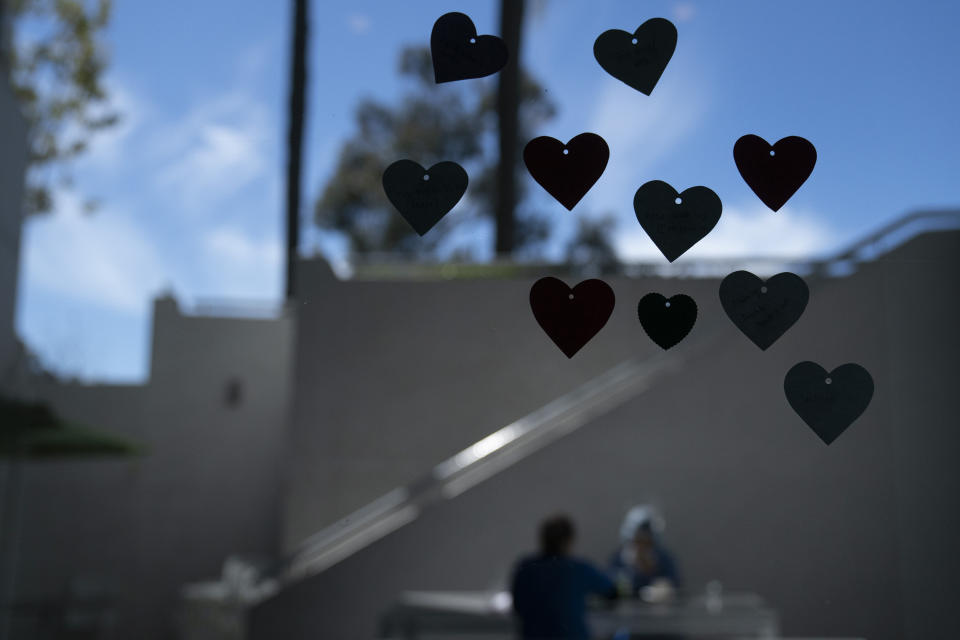 A cafeteria window is decorated with heart-shaped cutouts as hospital staff members eat their lunch in a recently reopened dining area at Mission Hospital in Mission Viejo, Calif., Friday, Feb. 19, 2021. California's virus cases, infection rates, and hospitalizations have dropped precipitously after reaching record highs in early January. (AP Photo/Jae C. Hong)