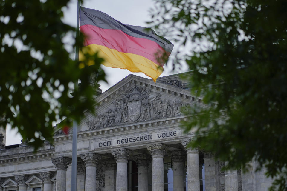 The German national flag waves in front of the German parliament building, the Reichstag Building, with the slogan: 'To The German People' in Berlin, Tuesday, Sept. 28, 2021. Germany's newly elected lawmakers are holding their first meetings as their parties digest the fallout of the election that reduced outgoing Chancellor Angela Merkel's bloc to its worst-ever result and start the process of putting together a new government. (AP Photo/Markus Schreiber)