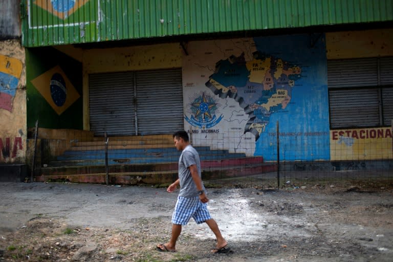 A man walks in front of one of the improvised refugee camps burnt down by local residents