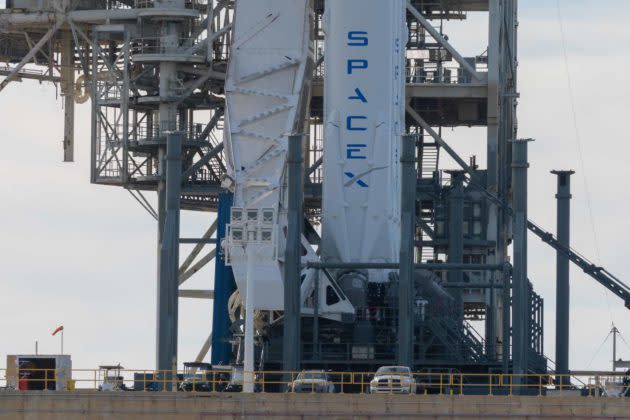 The enormous size of the Falcon Heavy is clear when compared to the cars parked below it. (GeekWire Photo/Kevin Lisota)