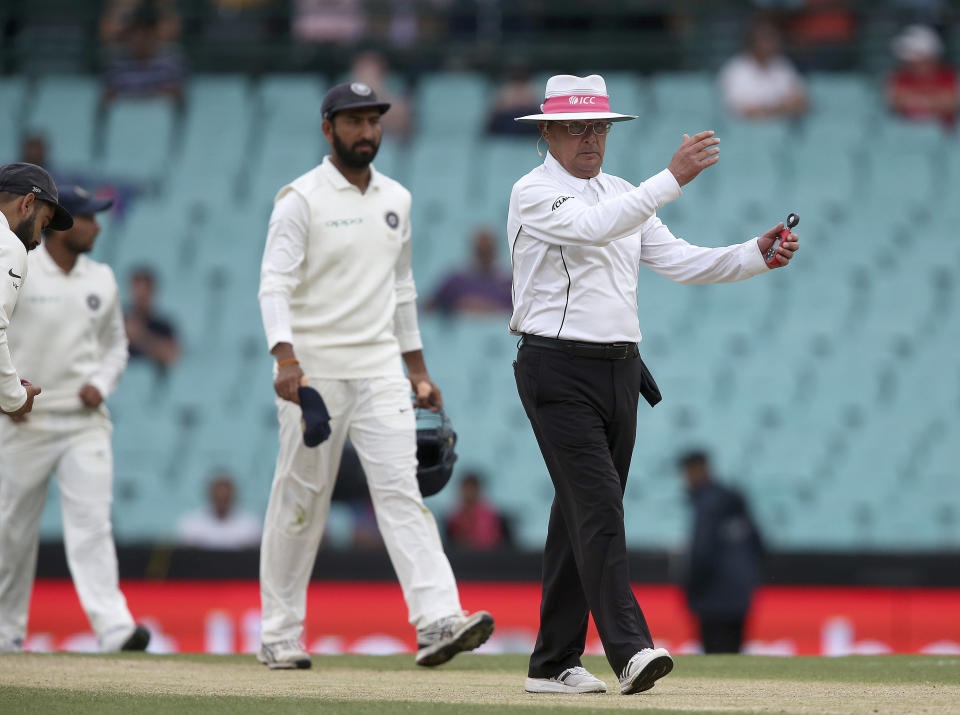 Umpire Ian Gould, right, signals that an early tea break will be taken due to poor light on day 4 of the cricket test match between India and Australia in Sydney, Sunday, Jan. 6, 2019. (AP Photo/Rick Rycroft)