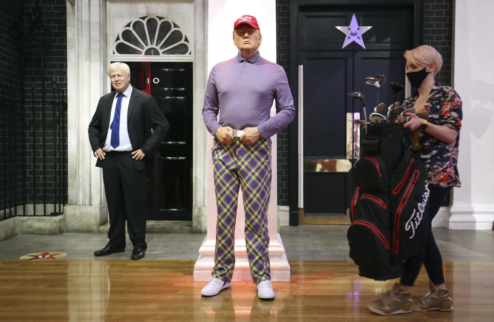 A member of the Madame Tussauds studios team places a set of golf clubs next to a wax figure of US President Donald Trump which has been re-dressed in golf wear following the 2020 US presidential election, in London, Wednesday, Nov. 4, 2020. Joe Biden was elected Saturday, Nov. 7, 2020 as the 46th president of the United States, defeating President Donald Trump in an election that played out against the backdrop of a pandemic, its economic fallout and a national reckoning on racism. (Jonathan Brady/PA via AP)