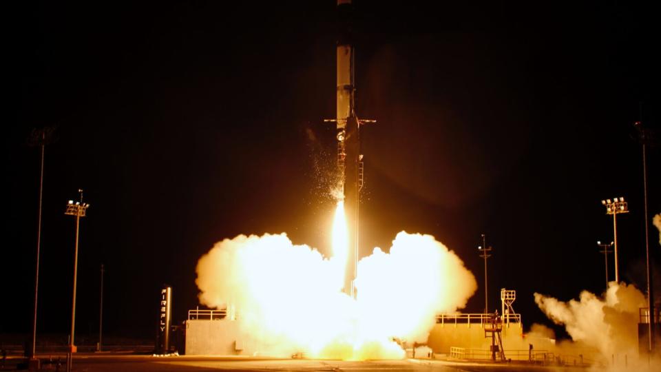 A rocket launches at night with a plume of fire beneath it