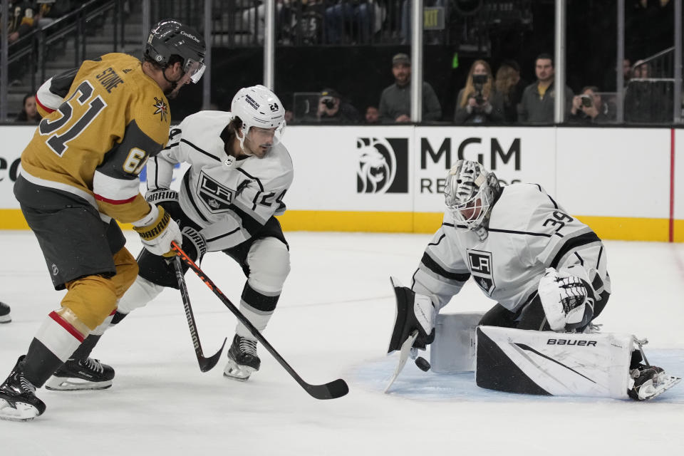 Los Angeles Kings goaltender Cam Talbot (39) stops the puck beside Vegas Golden Knights right wing Mark Stone (61) and Los Angeles Kings center Phillip Danault (24) during the second period of an NHL hockey game Wednesday, Nov. 8, 2023, in Las Vegas. (AP Photo/John Locher)