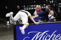 Dallas Mavericks guard Luka Doncic falls over a sign as he tried to save the ball from going out of bounds during the first half of the team's NBA basketball game against the Memphis Grizzlies on Tuesday, May 11, 2021, in Memphis, Tenn. (AP Photo/Wade Payne)