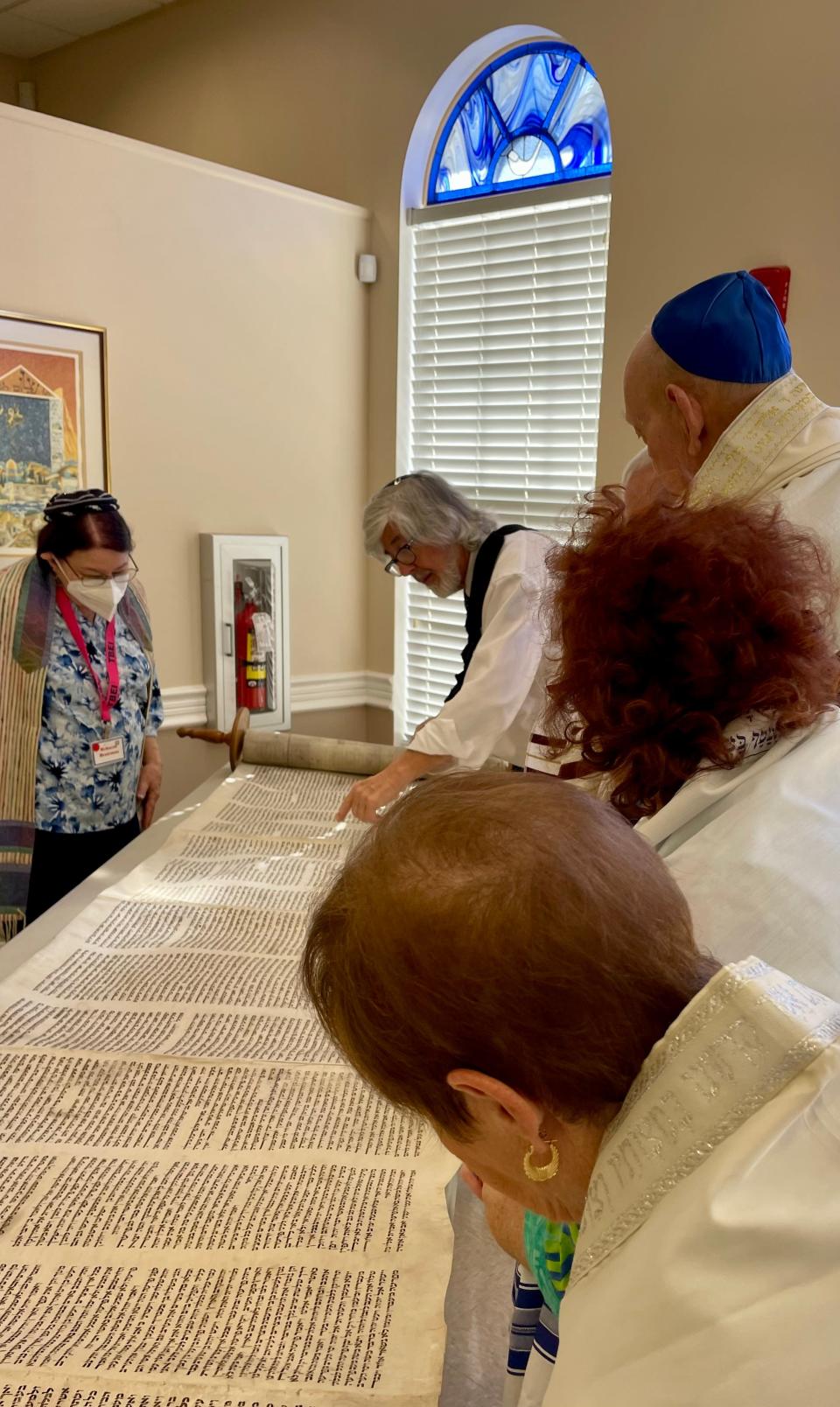 Rabbi Bruce Benson examines the Torah scroll, MST860,  with Temple Beth El Israel congregation members. It will be displayed in the synagogue after it is walked to the temple on April 15.