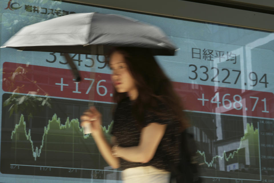 A woman walks past monitors showing Japan's Nikkei 225 index at a securities firm in Tokyo, Monday, July 31, 2023. Shares were mostly higher in Asia on Monday after Wall Street got back to climbing following more encouraging profit reports and the latest signal that inflation is loosening its chokehold on the economy. (AP Photo/Hiro Komae)